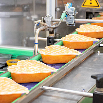 Heart-shaped HiPP toddler meal trays on a filling line