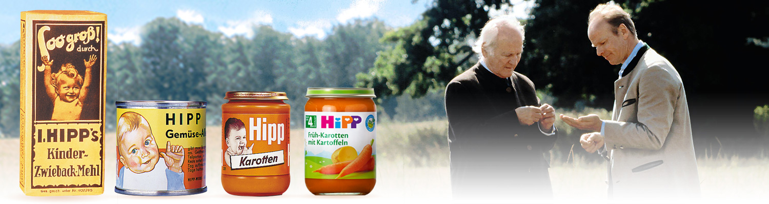 Two men are engaged in a conversation outdoors, with three containers of baby food products displayed in the foreground.